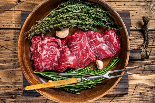 Prime Raw machete skirt beef steak in woode plate with herbs