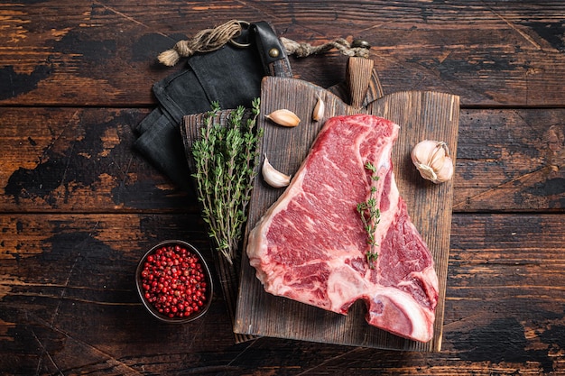 Prime Tbone beef vlees steak rauwe porterhouse steak op slager bord met kruiden Houten achtergrond Bovenaanzicht