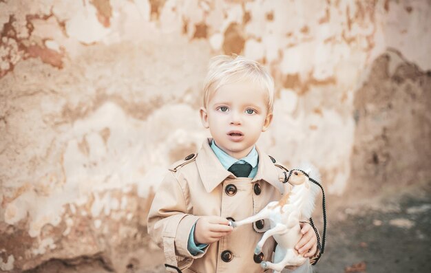 Prince on white horse small boy prince small kid with toy horse\
happy childhood childrens day little boy in vintage coat fashion\
look retro style playing toys do you like it toy in kid hand