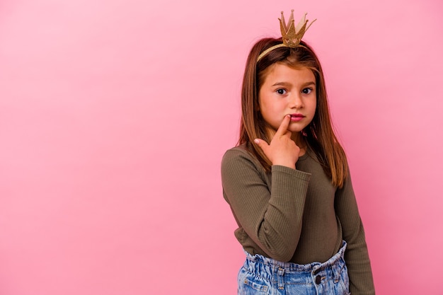 Prinsesje meisje met kroon geïsoleerd op roze ontspannen denken aan iets kijken naar een kopie ruimte.