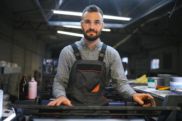 Print worker trying to fix the problem on computer to plate machine in printing shop