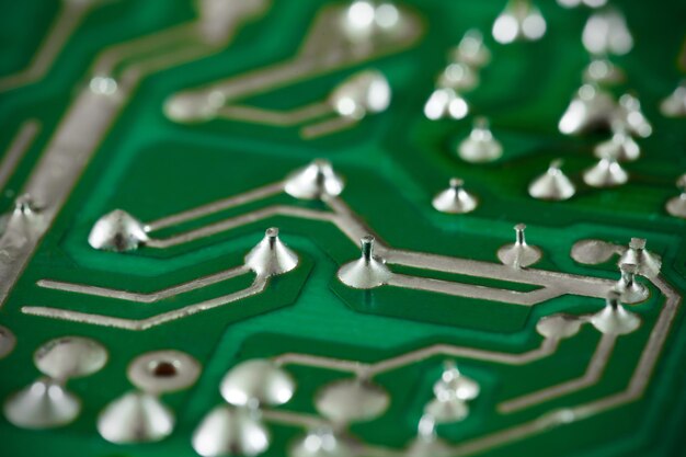 Photo printed circuit board green, electric, soldered legs of electrical components close-up macro view