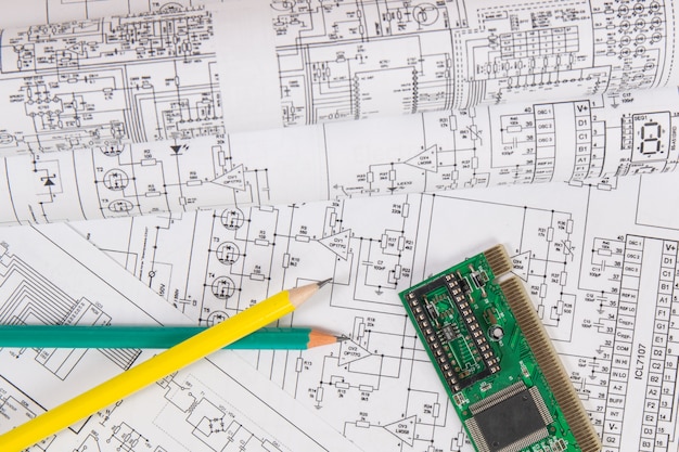 Печатные чертежи электрических схем, электронная доска и карандаши.