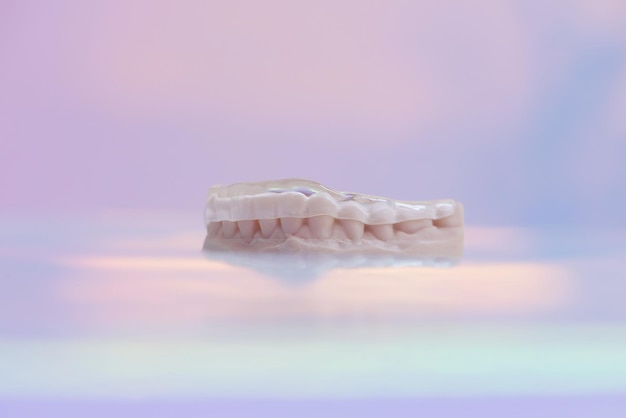 Printed transparent dental cap made of polymer on a light\
colorful background dental splint against