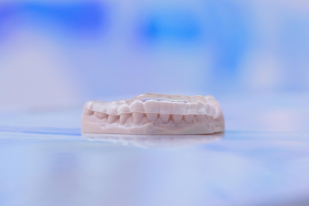 Printed transparent dental cap made of polymer on a light colorful background dental splint against