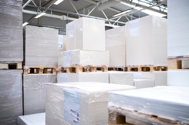 Printing house warehouse interior with large piles of blank sheets for print.