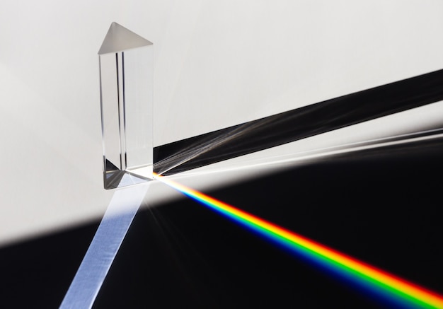 A prism dispersing sunlight splitting into a spectrum on a white background.