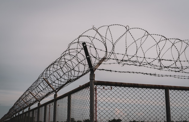 Prison security fence. Barbed wire security fence. Razor wire jail fence. Barrier border. Boundary security wall. Prison for arrest criminals or terrorists. Private area. Military zone concept.