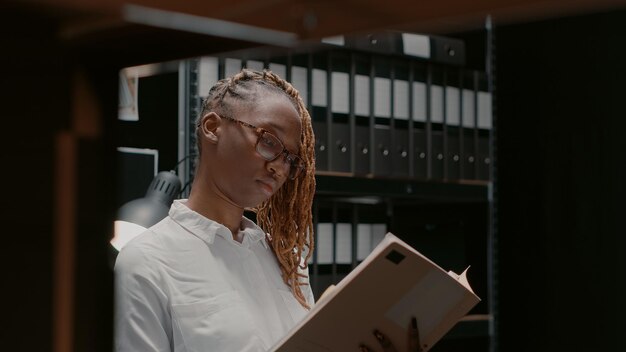 Photo private detective analyzing gathered case clues in incident room, examining photos and doing background check. police officer reading archive records and criminal evidence, studying clues.