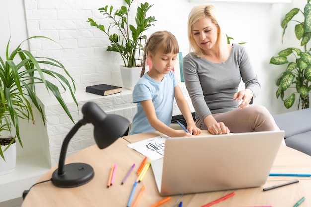 Private lesson. attentive young woman tutor teacher help little
girl pupil with studying math language correct mistakes explain
learning material. smiling mother assist small daughter with home
task.