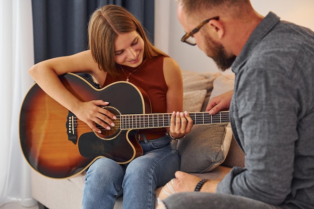 Private lesson Guitar teacher showing how to play the instrument to young woman