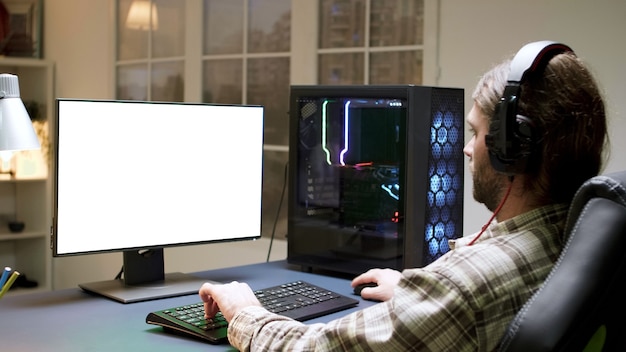 Pro bebaarde gamer met lang haar die videogames speelt op computer met groene mock-up.