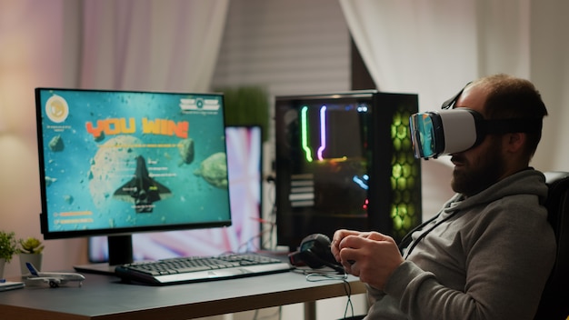 Foto pro cyber sport gamer che vince giocando ai videogiochi utilizzando l'auricolare vr. campionato di gioco sparatutto spaziale virtuale nel cyberspazio, giocatore di esport che si esibisce su un potente computer durante il torneo di gioco