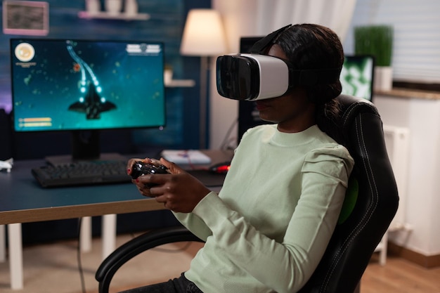 Pro gamer woman wearing virtual reality headset holding gaming\
joystick playing space shooter videogames during online\
competition. concentrated gamer playing games using rbg computer\
equipment