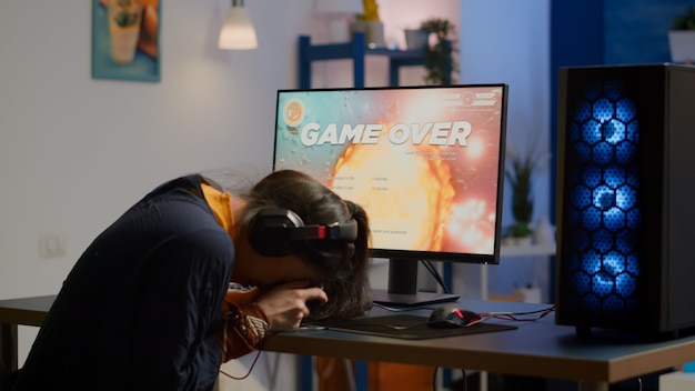 Pro woman gamer losing space shooter video game competition on professional powerful computer with wireless controller. Professional player streaming online game using professional joystick and headse