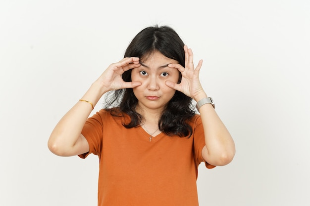 Proberen de ogen te openen van een mooie aziatische vrouw die een oranje t-shirt draagt dat op een witte achtergrond wordt geïsoleerd