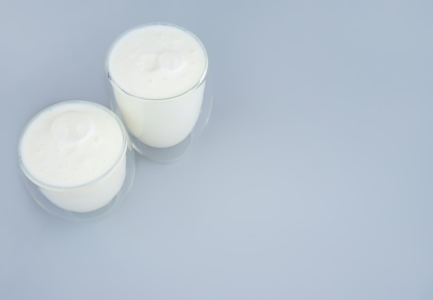 Probiotic drink, buttermilk or yogurt. Kefir in glass on minimalistic blue background. Bacteria Gut health, fermented products for gastrointenstinal tract. Top view. Copy space.