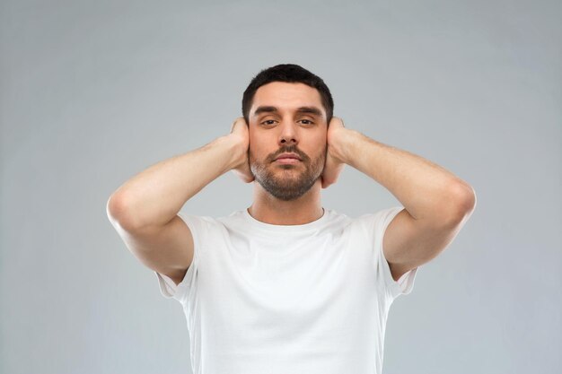 probleem, emotie, stress, gehoorprobleem en mensenconcept - Latijnse man die zijn oren bedekt met handpalmen