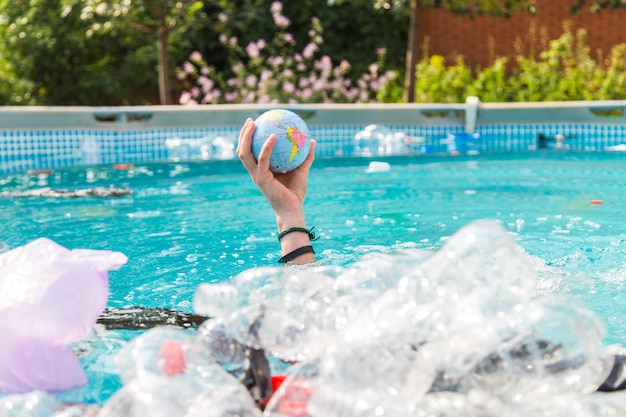 Probleem van afval, plastic recycling, vervuiling en milieuconcept - Plastic afvalvervuiling in de wateromgeving, Earth globe drijft in de prullenbak