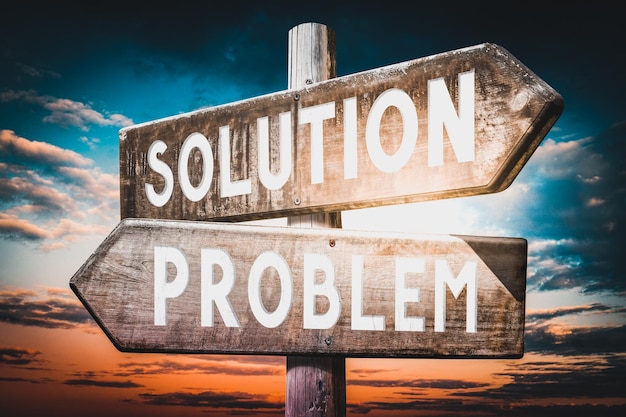 Problem solution wooden signpost with two arrows sunset sky in background