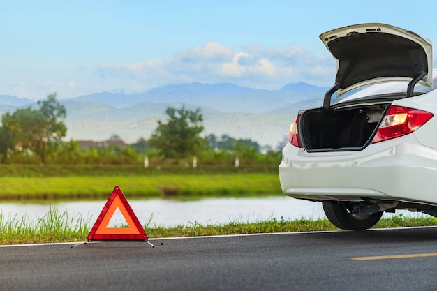 Problems car and a red triangle warning sign on the road