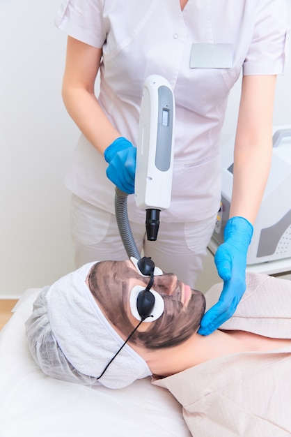 Процедура карбонового пилинга лица в клинике лазерной косметологии.