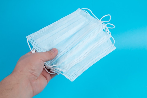 Procedure mask from bacteria in hand. Protective medical mask on blue background