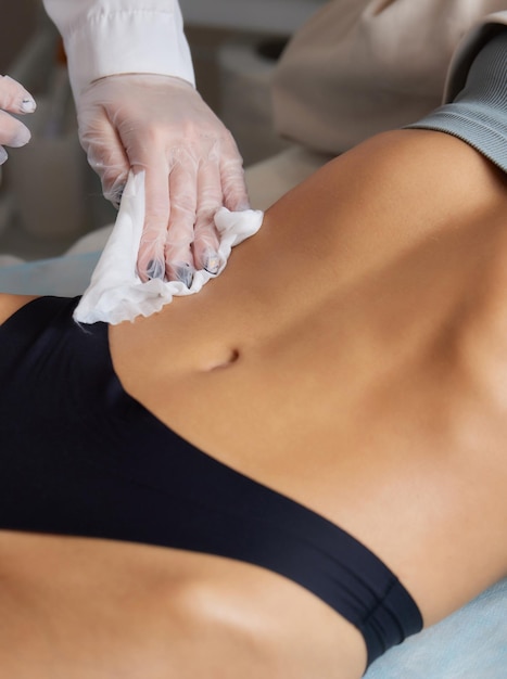 女性の腹部のキャビテーション腹マッサージでセルライトを除去する手順体重減少のための超音波マッサージ外科的介入なしの女性の姿の矯正おなかのクローズアップ