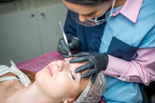 Procedure voor microblading van wenkbrauwen Een meester in zwarte handschoenen doet een mengnaald van de wenkbrauw van model39