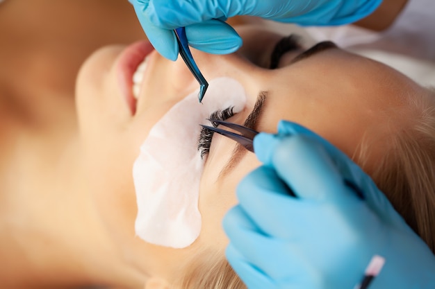 Procedure voor wimperverlenging, professionele stylist die vrouwelijke wimpers verlengt.