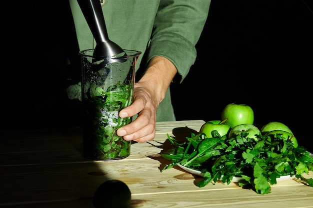 Proces om groene detox smoothie met mixer te bereiden, jonge mensenhanden die gezonde smoothie koken.