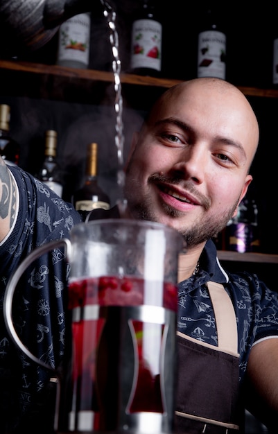 Proces thee zetten, theeceremonie. Barman giet heet water in de waterkoker om bessenthee te zetten