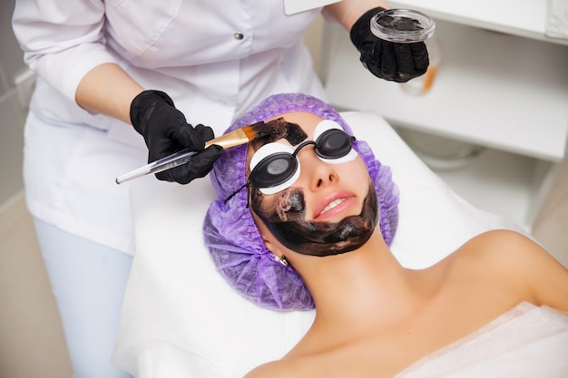Proces van carbon gezicht laser peeling procedure in schoonheidssalon. laserpulsen reinigen de huid van het gezicht. hardware cosmetologie behandeling. huidverjonging. jonge vrouw met koolstof nanogel op haar gezicht