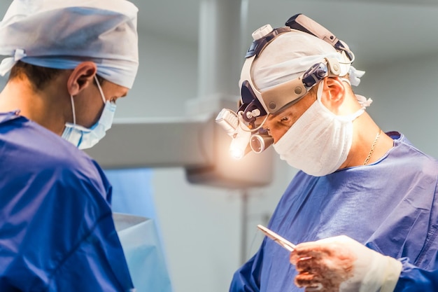 Proces van chirurgische operatie met behulp van medische apparatuur Twee chirurgen in de operatiekamer met chirurgische apparatuur en in een verrekijker Medische achtergrond