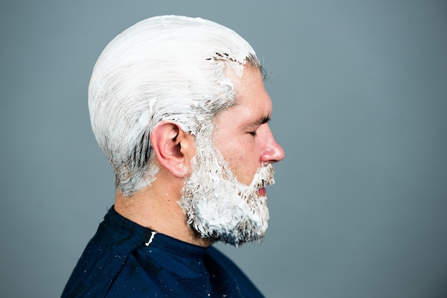 Proces van een kerel haarkleur bij kapper. Stylist man met haarverf en borstel kleuren haar.