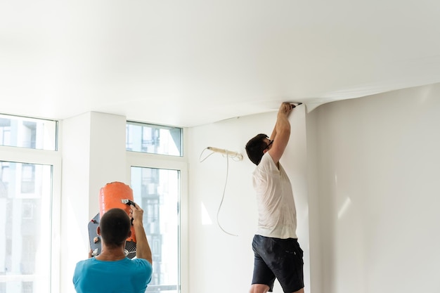 Proces van het installeren van spanplafond in de hal. Close-up van de hand van de mens met een hulpmiddel.