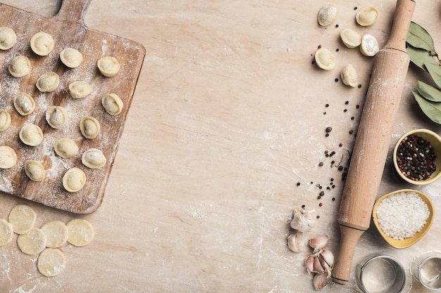 Proces van het maken van dumplings op houten tafel bedekt met bloem. Zelfgemaakte ongekookt voedsel en ingrediënten.