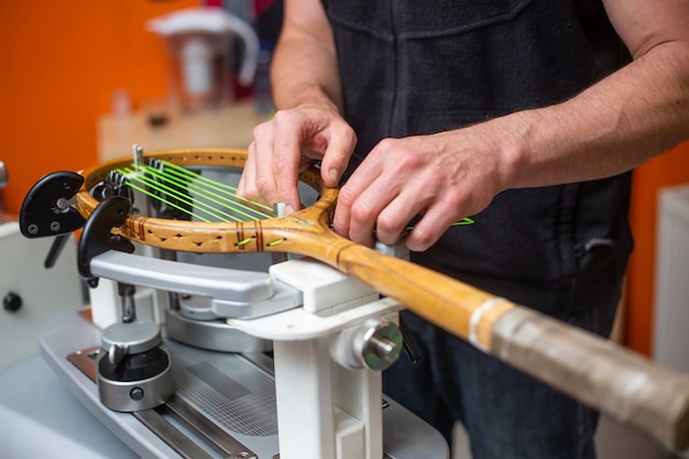 Proces van het rijgen van een tennisracket in een tenniswinkel, sport- en vrijetijdsconcept, onderhoud en tunning tennisracket