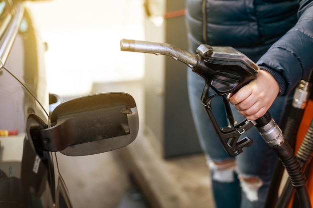 Proces van het tanken van een auto met benzinebrandstof bij de pomp van het tankstation die brandstofmondstuk in brandstof vult...