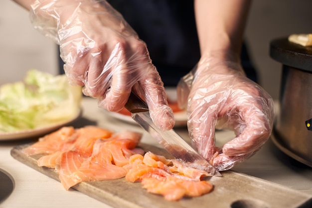 Proces van het voorbereiden van componenten voor voedsel snijden met mes stukjes vis op snijplank voor het koken van voedsel close-up