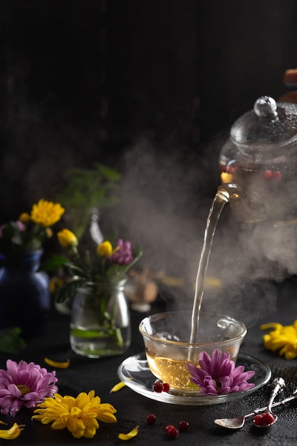 Process brewing teadark mood the steam from hot tea is poured
from the kettle flowers hot food and healthy meal concept high
quality photo