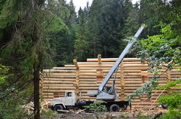 Il processo di costruzione di una casa in legno da travi in legno di forma cilindrica. gru in condizioni di lavoro