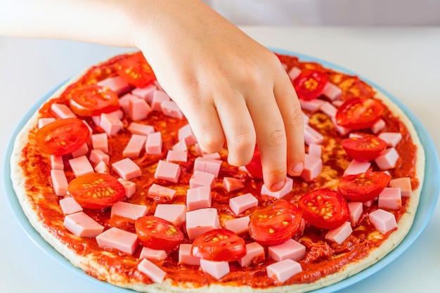 Process of cooking homemade pizza by child.