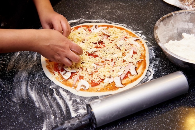 Foto il processo di cottura della pizza con carne, funghi, pomodori e formaggio.