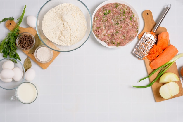 The process of cooking Uzbek manti at home, the ingredients are meat, vegetables, dough. top view on a light background.