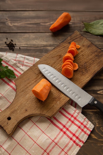 The process of cutting carrots into circles on a cutting board on a dark wooden background