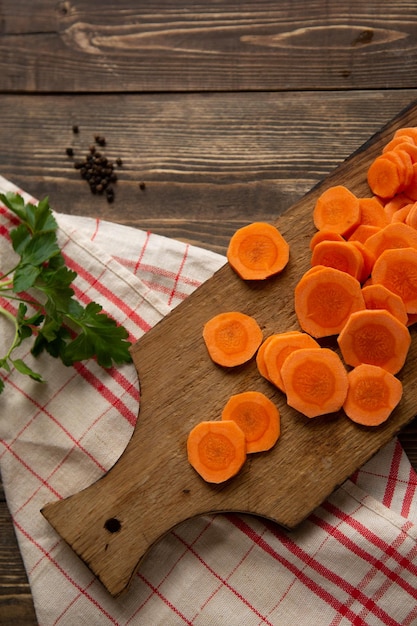 The process of cutting carrots into circles on a cutting board\
on a dark wooden background