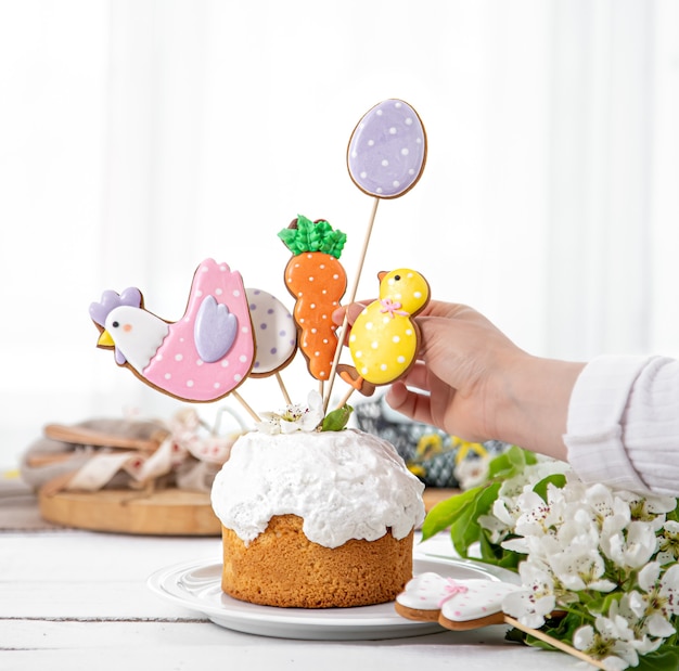 The process of decorating a festive cake with gingerbread and flowers. The concept of preparing for the Easter holiday.