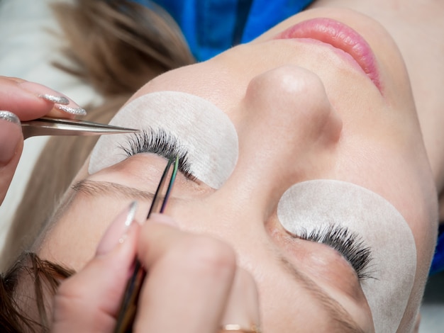 Process of eyelash extension in a beauty salon. Create volume in the lashes.