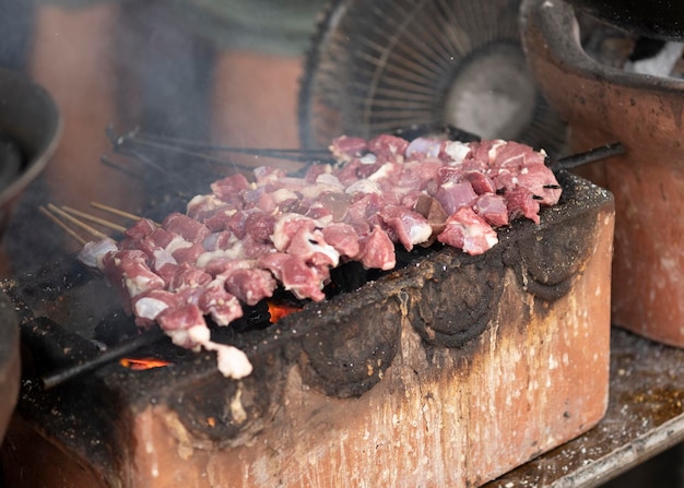 Процесс приготовления на гриле и приготовления традиционной еды Sate Klatak из Джокьякарты, сатай из баранины.